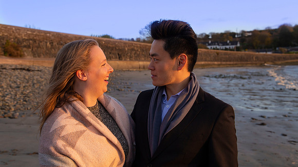 Couple walking on a beach during an engagement photo session in Cork, Ireland