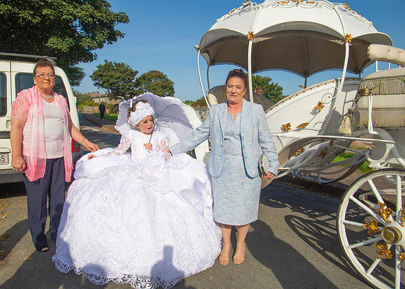 Young girl with her parents on her First Communion day photographed at the family home in Cork, Ireland by FlashFocus.org